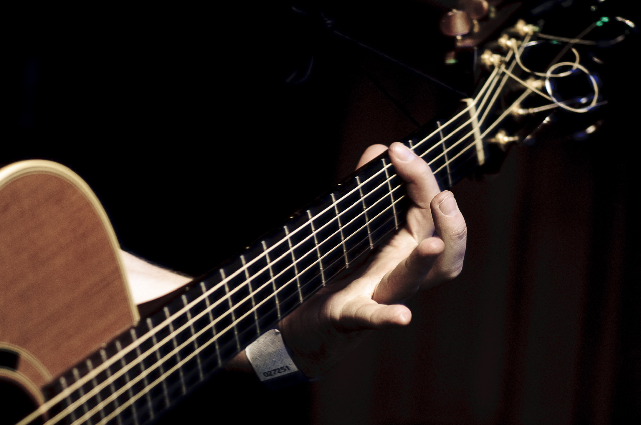 Close-up of a hand playing chords on an acoustic guitar